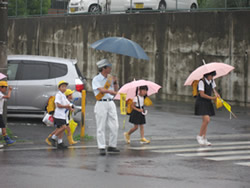 Employee holding flag for children going to school in the rain